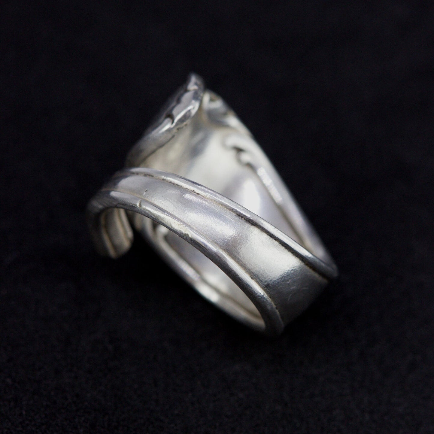 Silver ring with wavy design on a black background
