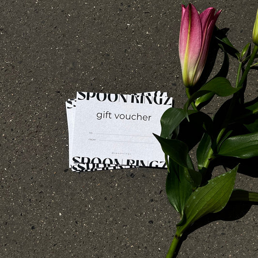 Floral arrangement with a gift voucher on a gray surface