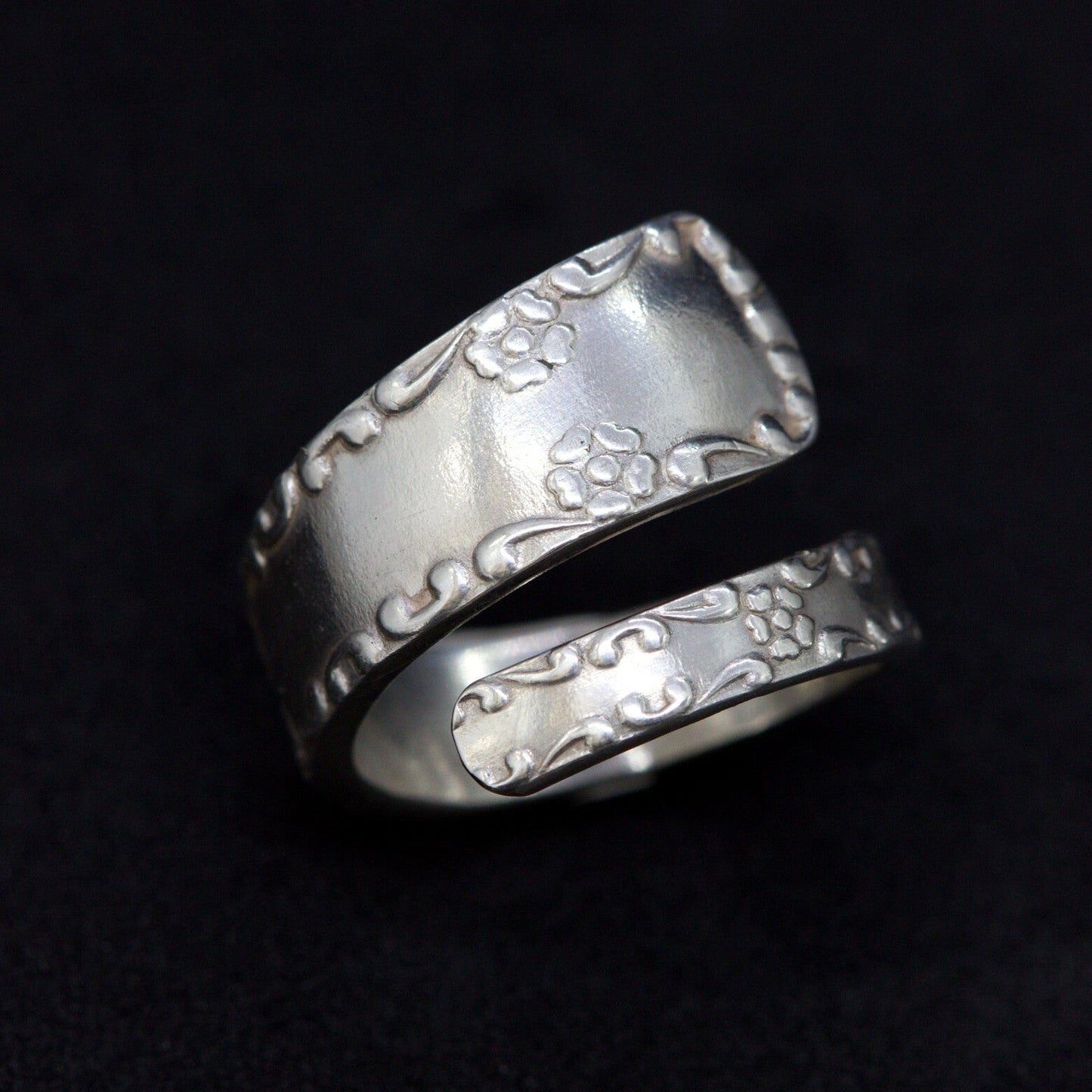 Silver ring with engraved design on a black background