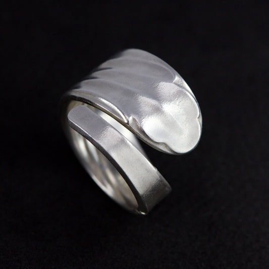 Silver ring with a textured design on a black background