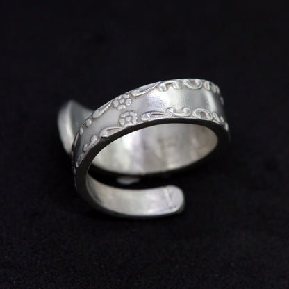 Silver ring with engraved design on a black background