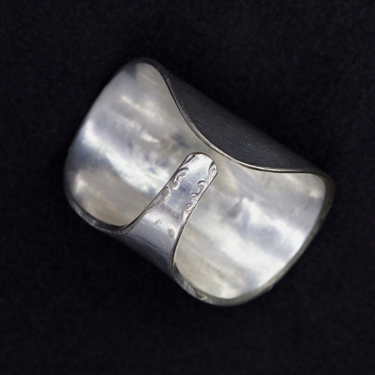Silver ring with a textured surface on a black background