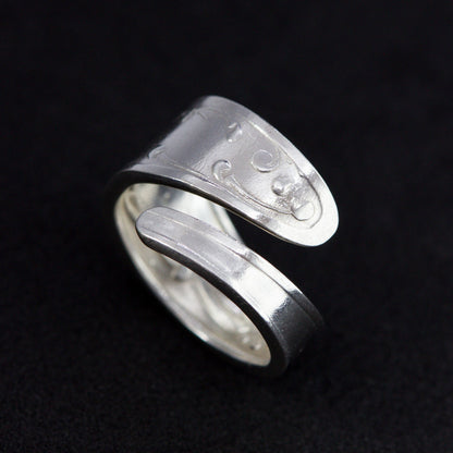 Silver ring with engraved design on a black background
