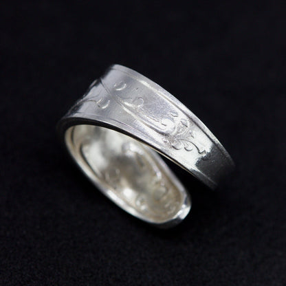 Silver ring with engraved design on a black background