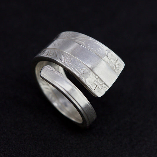 Silver ring with textured design on a black background