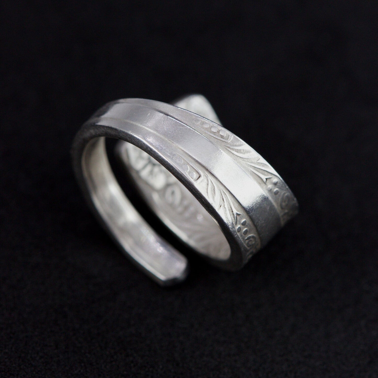 Silver ring with engraved design on a black background