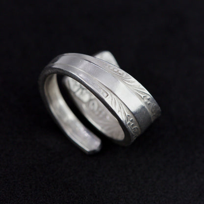 Silver ring with engraved design on a black background