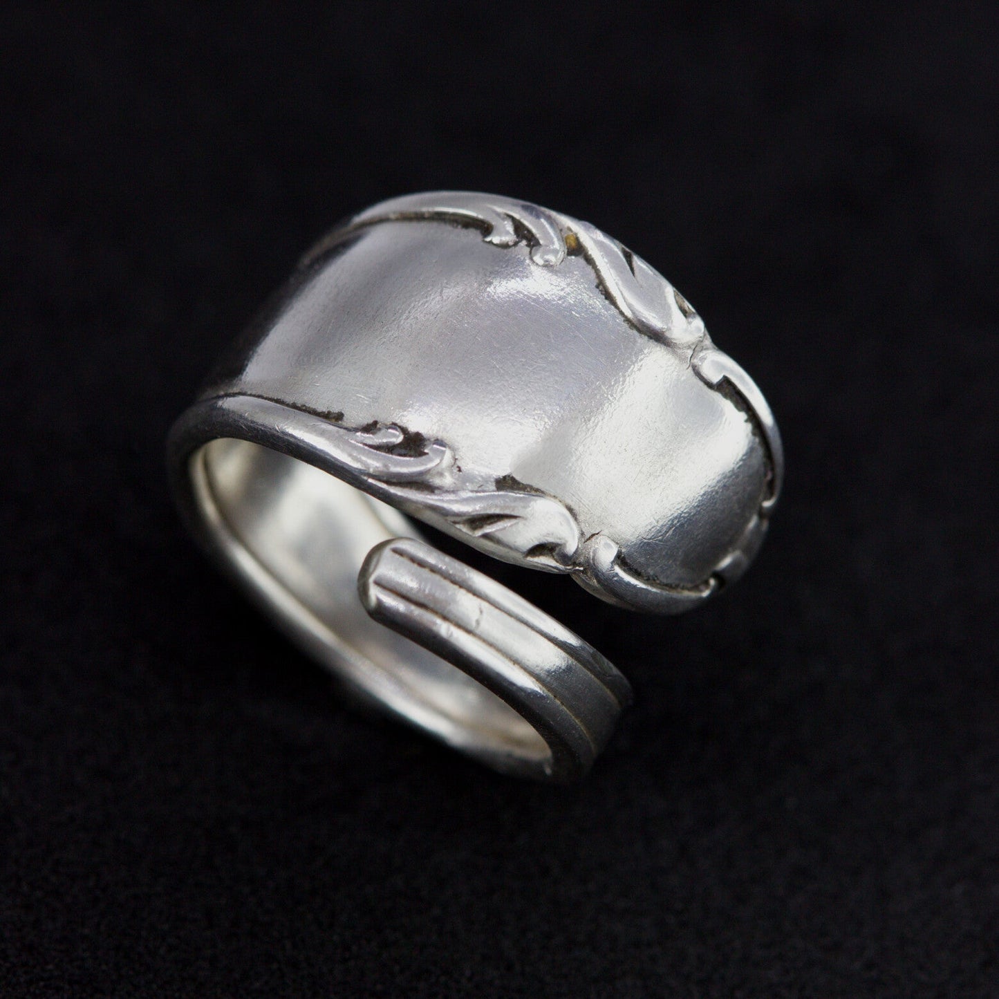 Silver ring with intricate design on a black background