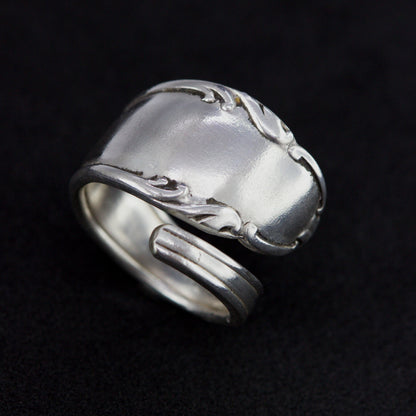 Silver ring with intricate design on a black background