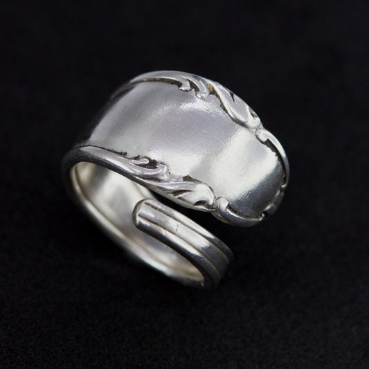 Silver ring with intricate design on a black background