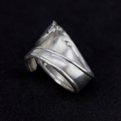 Silver ring with wavy design on a black background