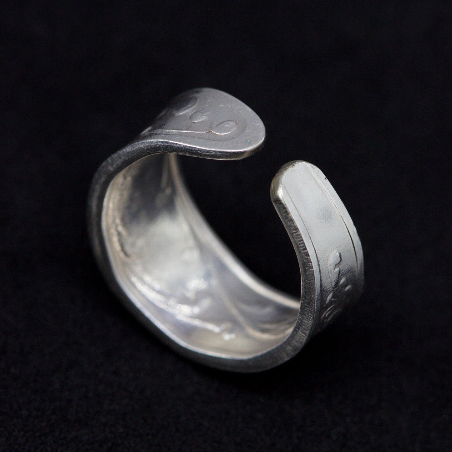 Silver ring with engraved text on a black background