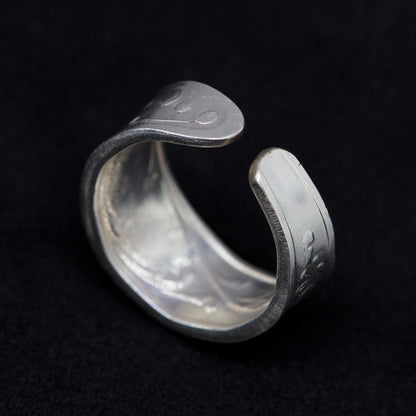 Silver ring with engraved text on a black background