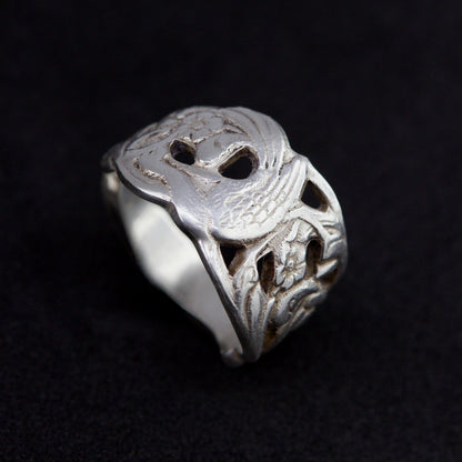 Silver ring with intricate design on a black background