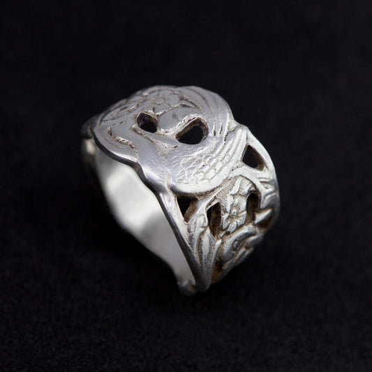 Silver ring with intricate design on a black background