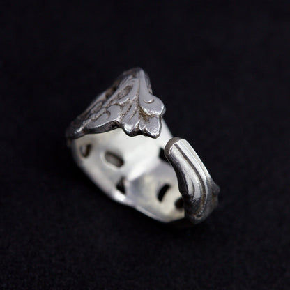 Silver ring with intricate design on a black background