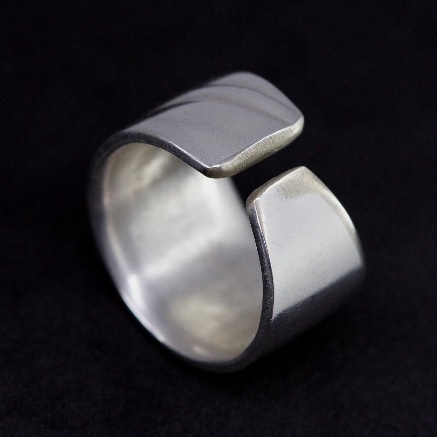 Silver ring with a unique design on a black background